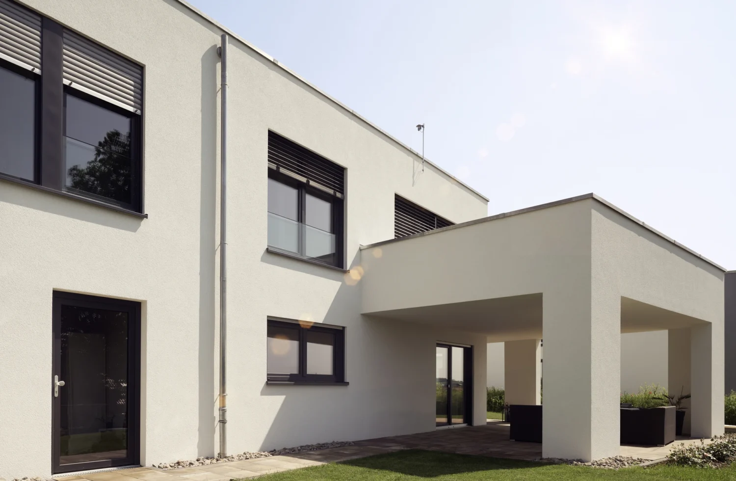 Modernes Wohnhaus mit Flachdach und überdachter Terrasse bei Sonnenschein