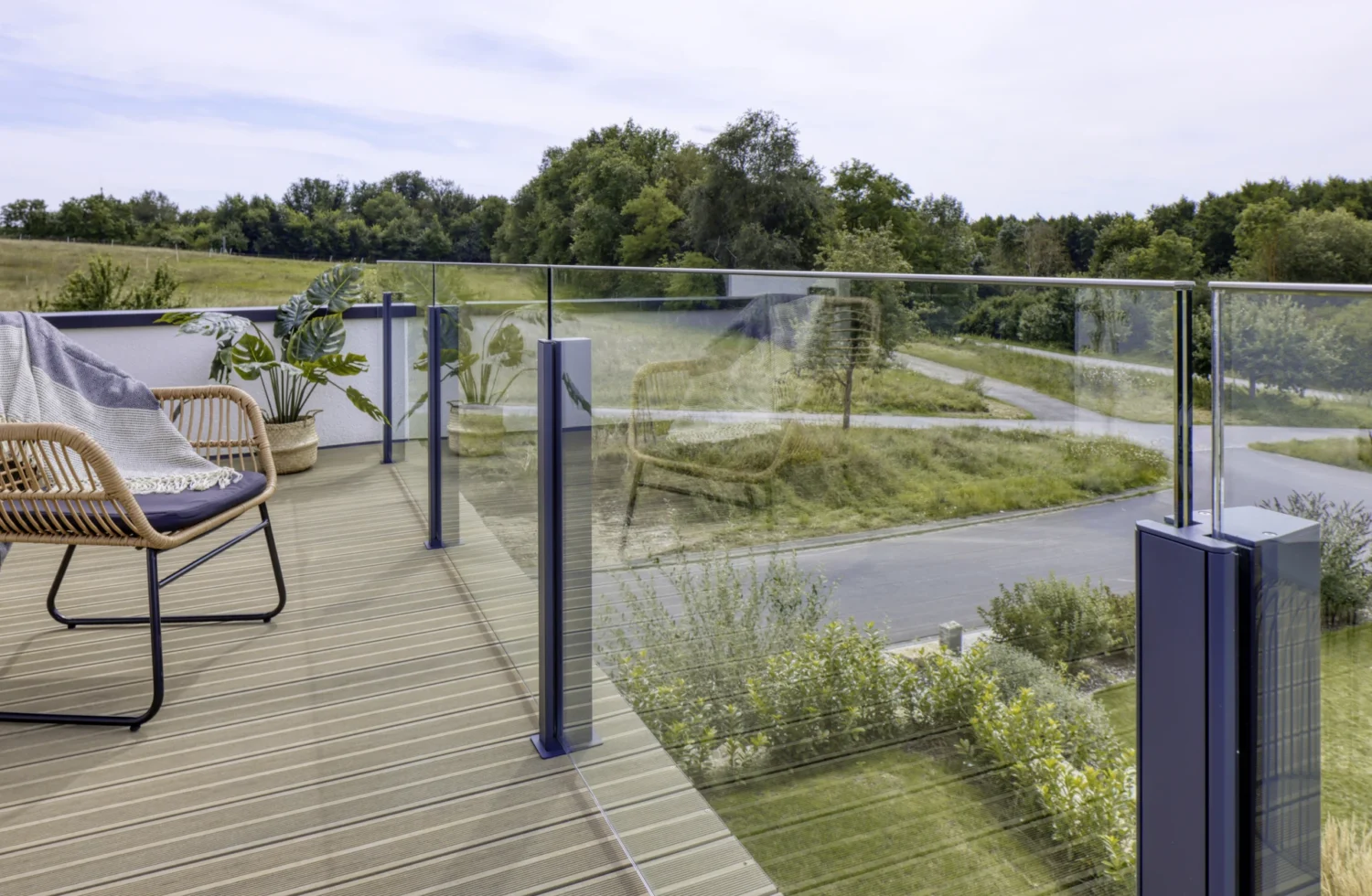Moderne Terrasse mit Glasgeländer und gemütlichem Rattanstuhl