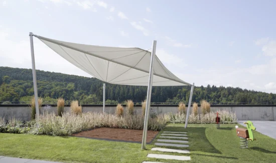 Moderne Sonnensegel über einem Spielbereich mit grüner Landschaft im Hintergrund