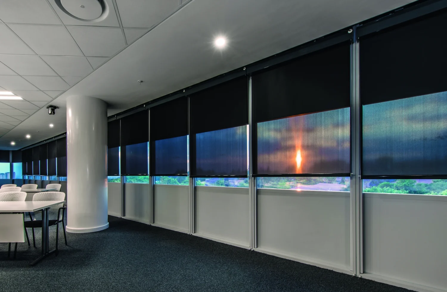 Moderne Büroumgebung mit Sonnenschutzrollos bei Sonnenuntergang